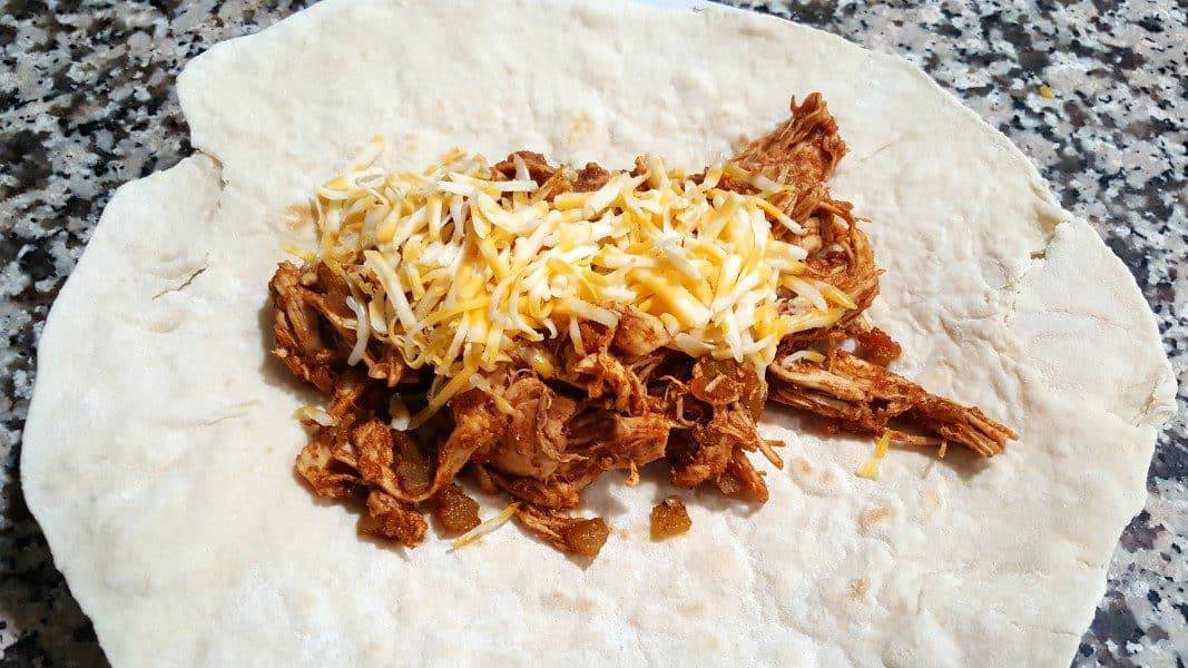 chicken chimi mixture topped with cheese on a burrito size tortilla