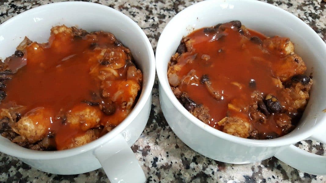 ground beef, black beans, tater tot, and colby jack cheese mixture topped with enchilada sauce in two baking dishes
