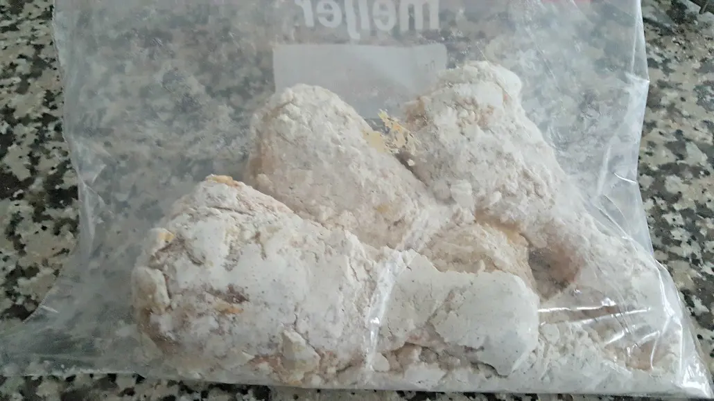 chicken drumsticks shaking in flour in a baggie