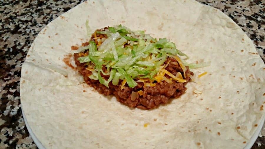 Bean and Beef Burrito on a tortilla with cheese, lettuce.