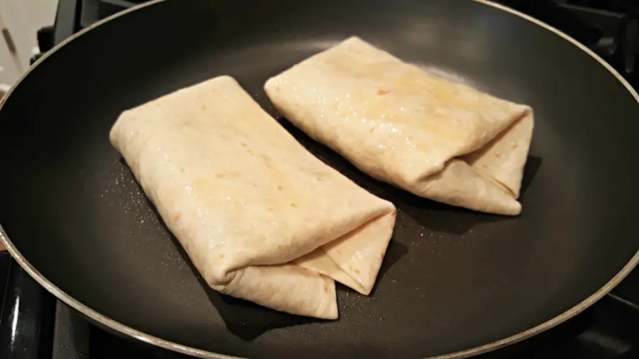 chicken bean and cheese burrito frying in a pan.