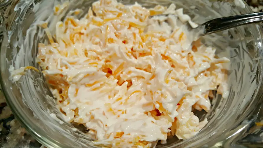 mixing sour cream and shredded cheese in a bowl
