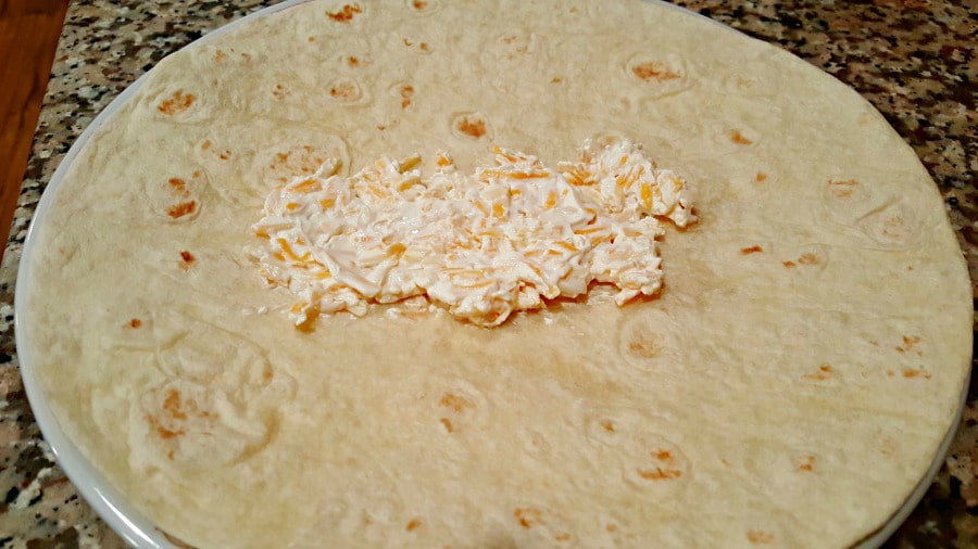 adding sour cream and shredded cheese to chimichangas