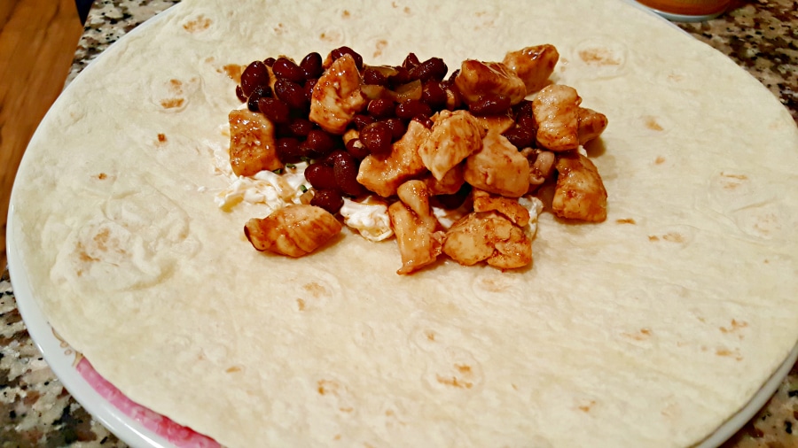 adding chicken and black bean mixture to chimichangas