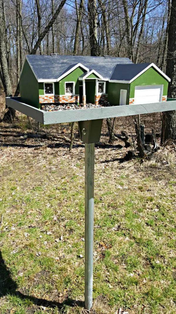 a diy bird feeder mounted on a post in the front yard