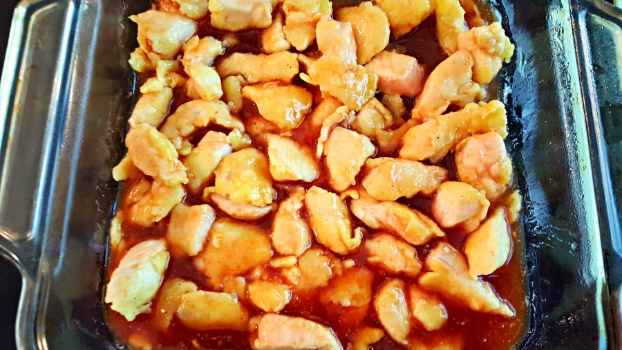chicken in a baking dish covered in homemade sweet and sour sauce