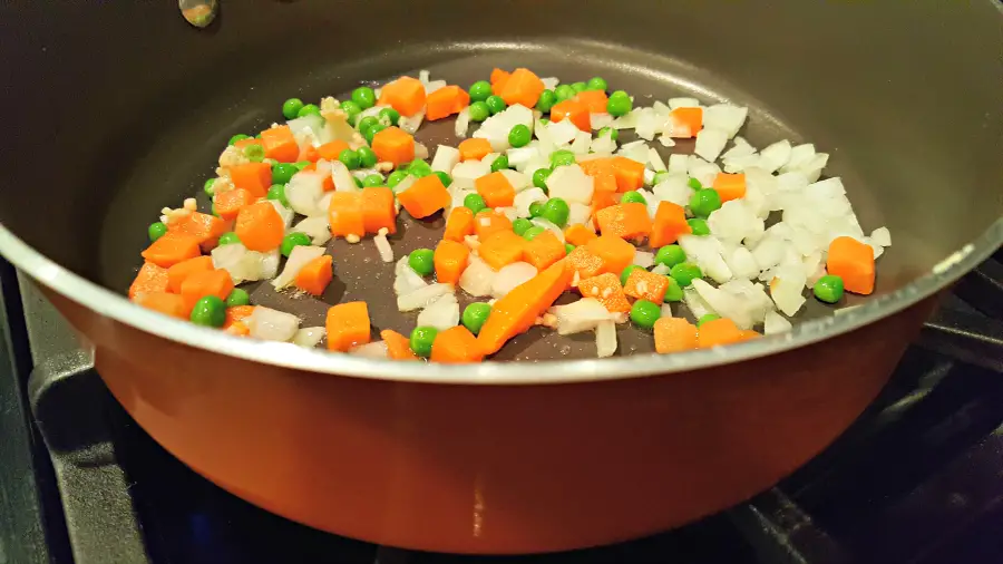 carrots, peas and onions cooking in a pan