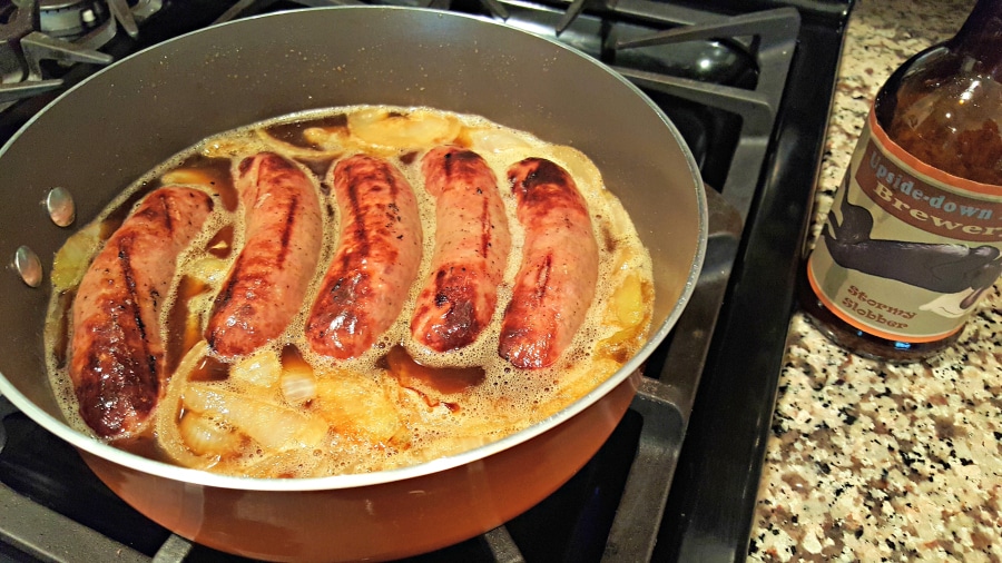 Beer Simmered Brats and Caramelized Onions cooking in a pan.