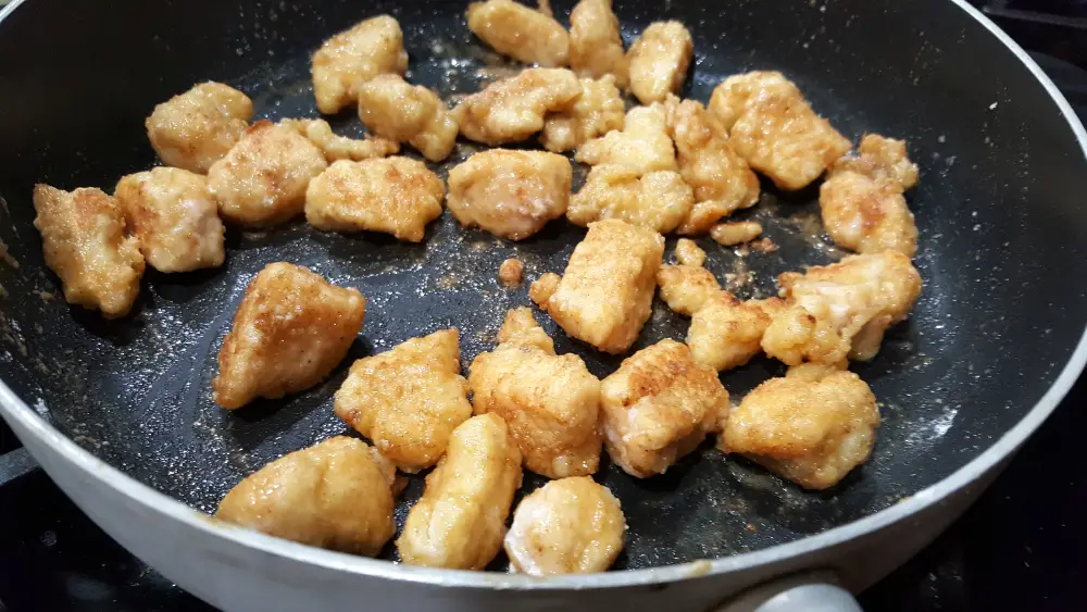 breaded chicken cooking in a frying pan.
