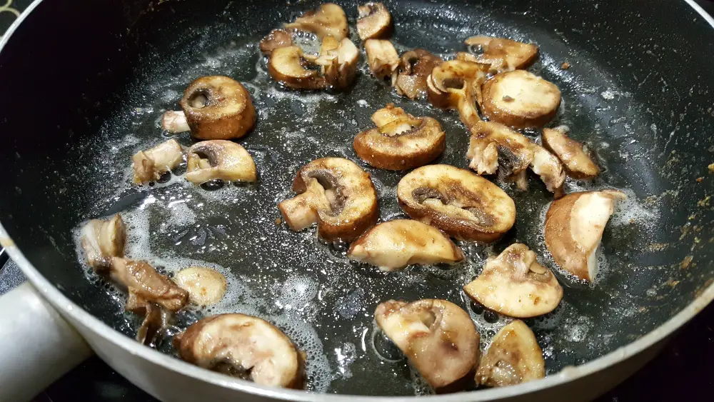 mushrooms and butter cooking in a frying pan.