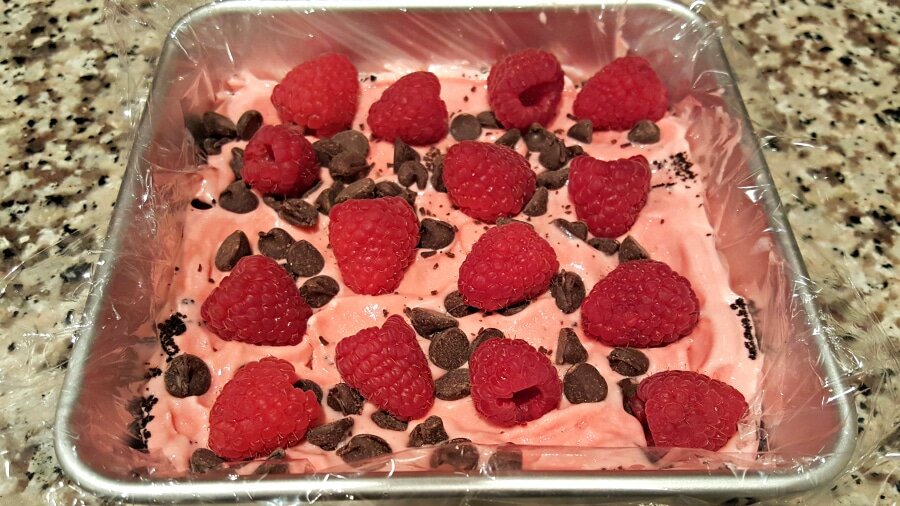 chocolate chips and fresh raspberries layered on cake in cake pan