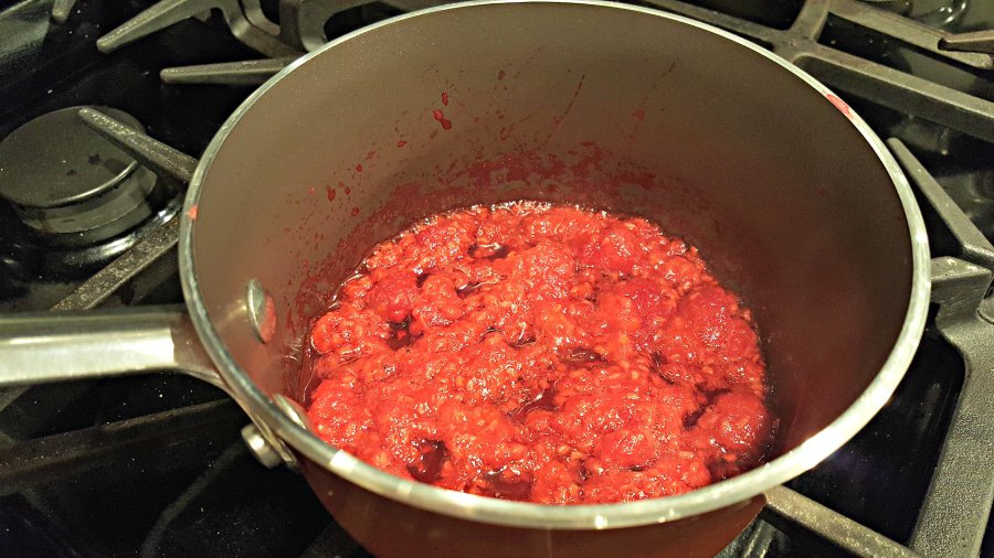 fresh raspberries and water simmer on the stove in a pan