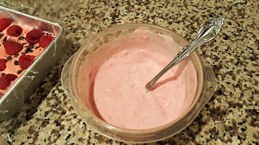 cooked raspberries and ice cream mixed together in a bowl next to freezer cake