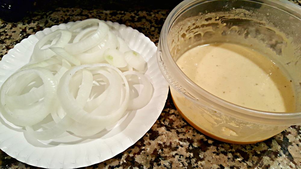 slice onions on a plate and a bowl of beer batter.