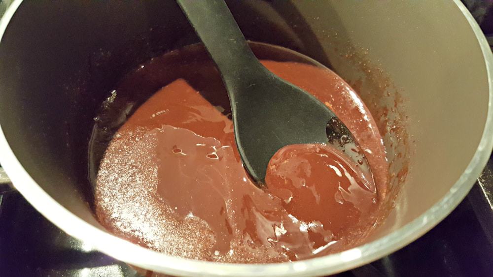 chocolate sauce cooking in a pan with a spoon