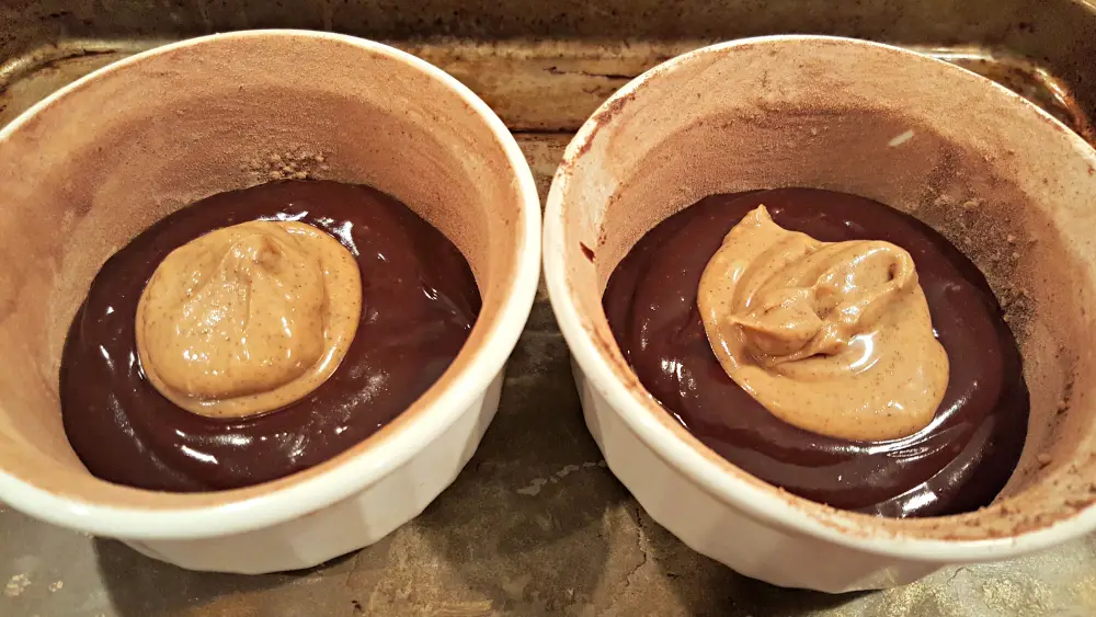 two ramekins with some choclate cake batter and some peanut butter lava sauce inside