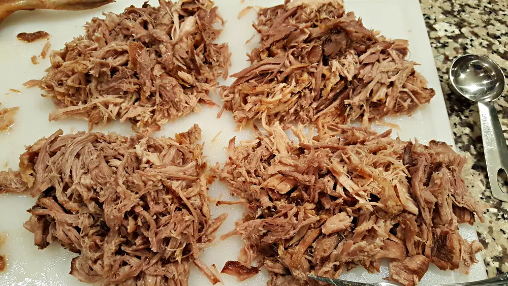 pulled pork divided into 4 portions on a cutting board