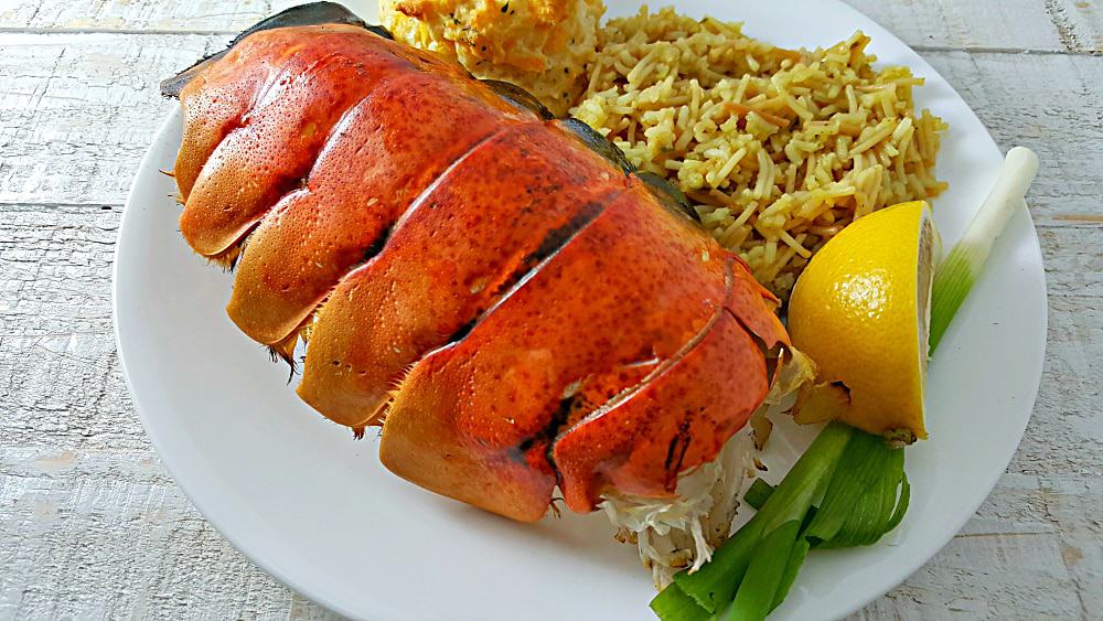 a large Grilled Lobster Tail on a plate with rice