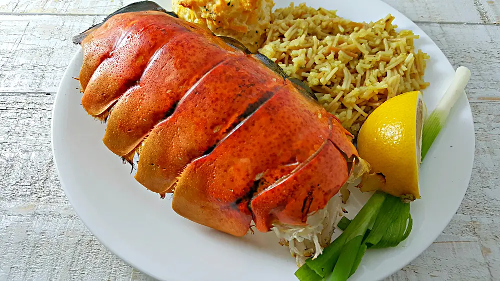 a large Grilled Lobster Tail on a plate with rice