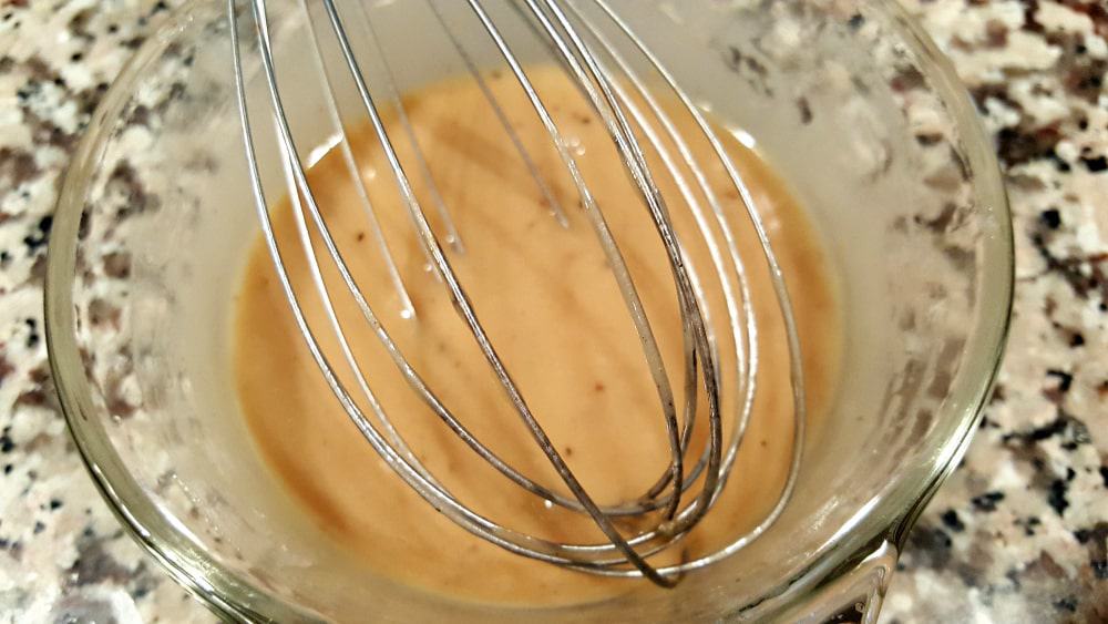 honey mustard sauce ingredients in a bowl with a whisk