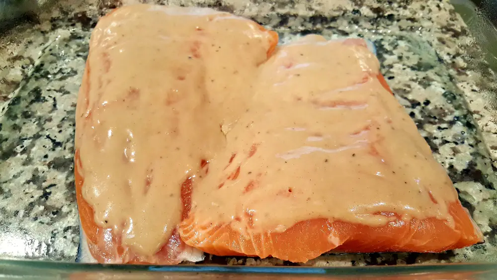 two salmon filets in a baking dish topped with honey mustard sauce