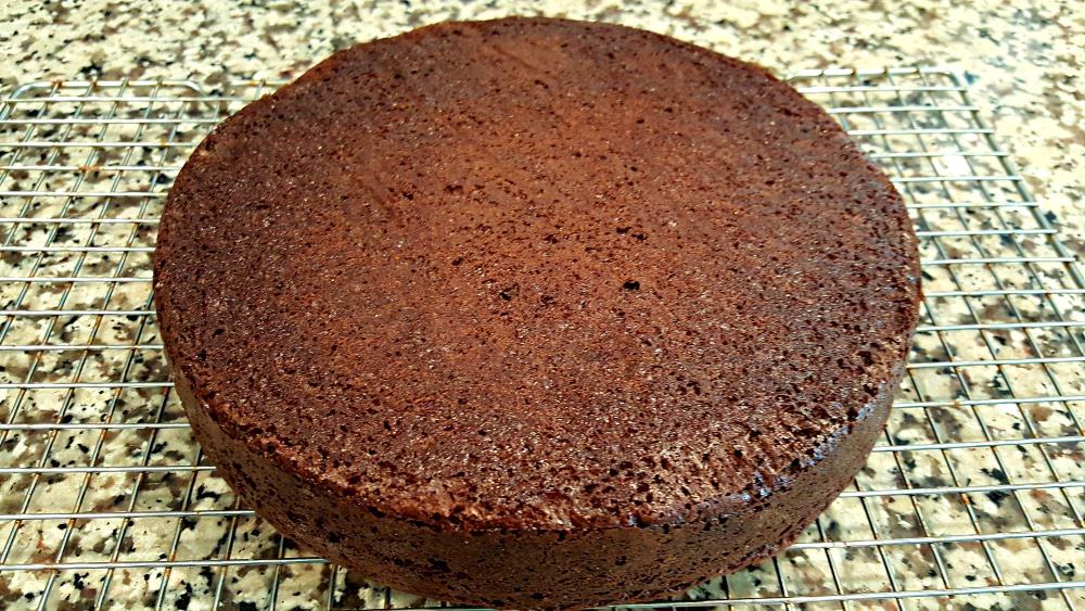 round chocolate cake cooking on a rack