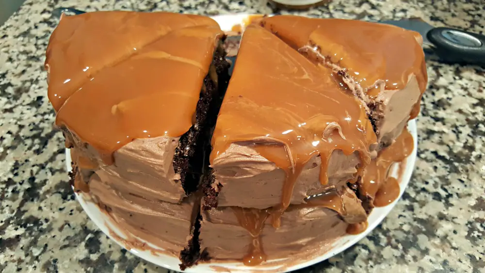 four pieces of two layer chocolate cake and salted caramel topping on a plate