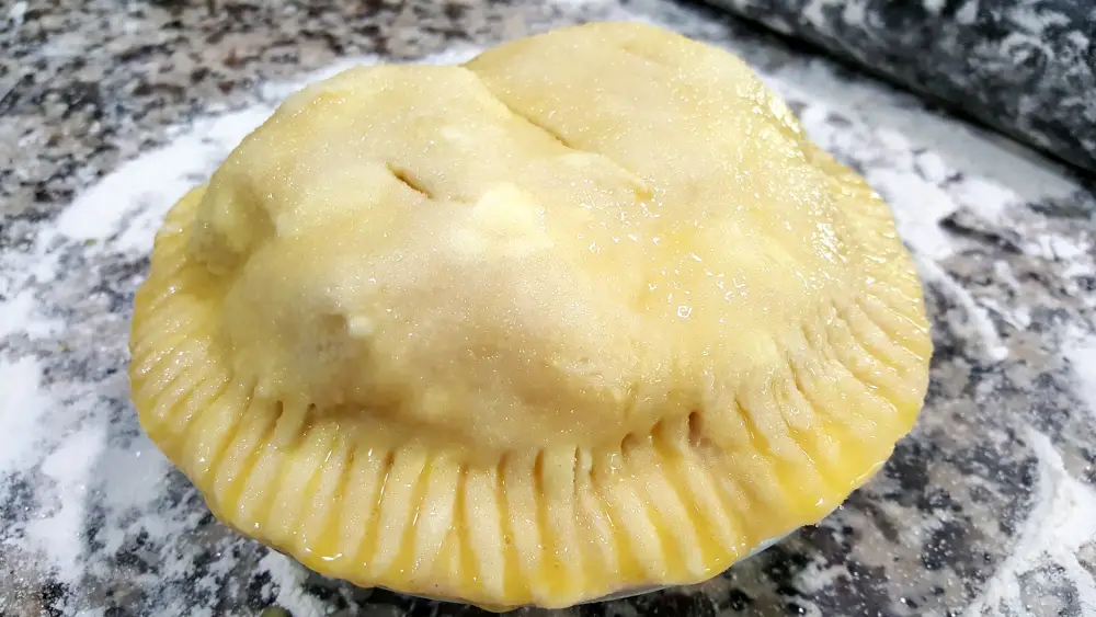 an unbaked pie with egg wash on the top.