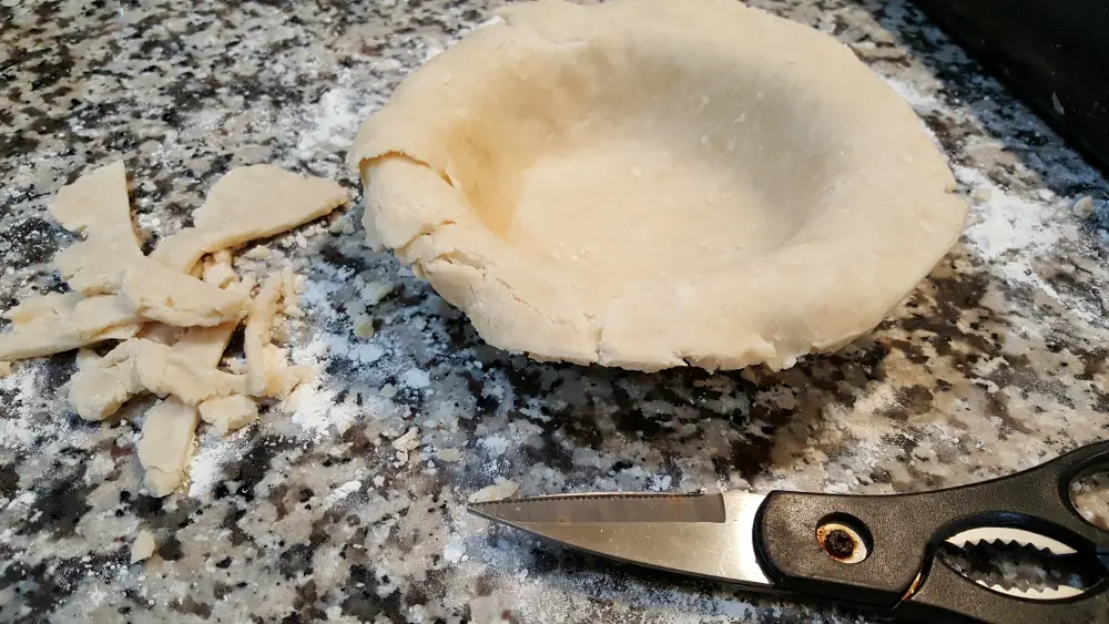 pie crust placed in the pie pan then edge trimmed.