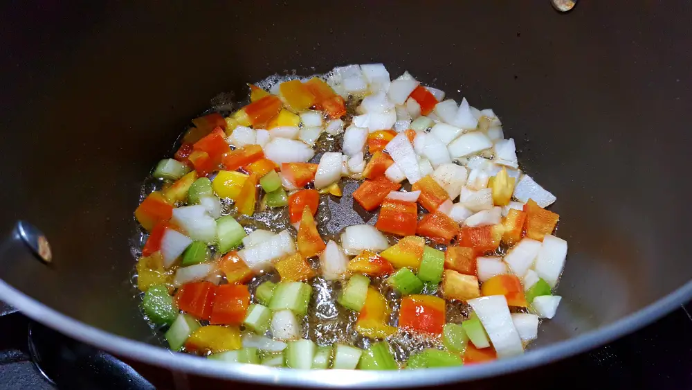 celery, onion, bell pepper and minced garlic frying in a pan