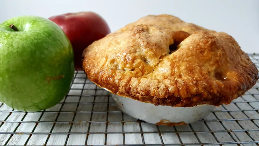 a small apple pie with two apples on the side.