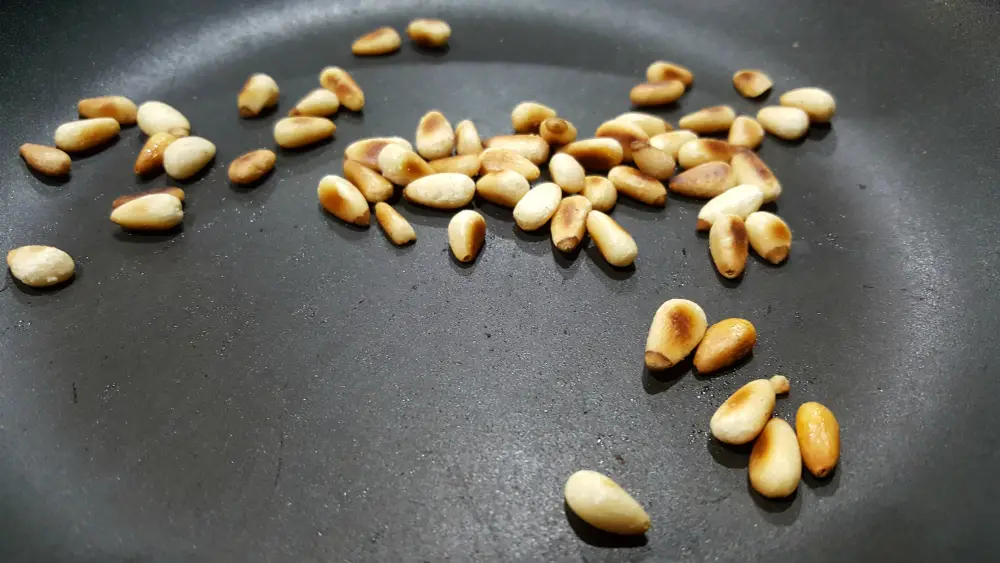 pine nuts cooking in a frying pan.