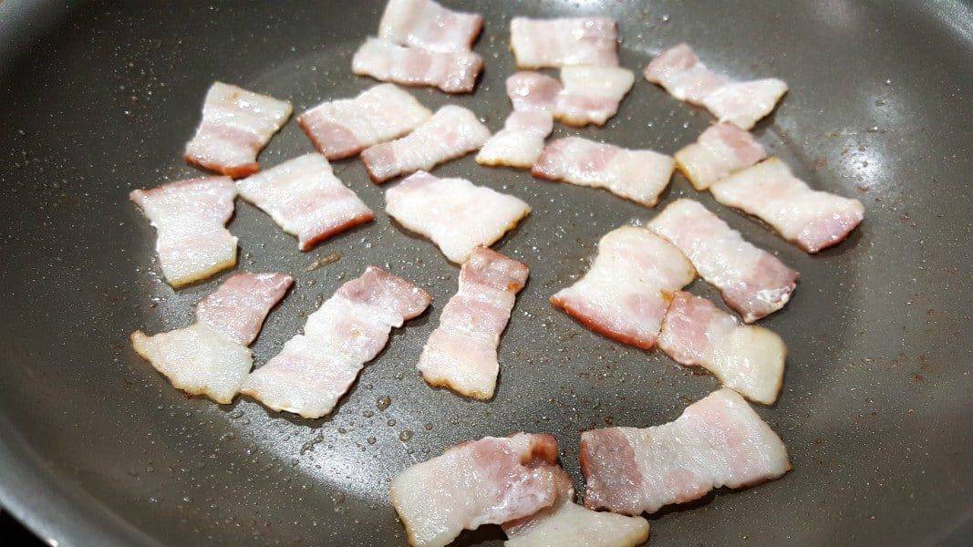 bacon pieces frying in a pan