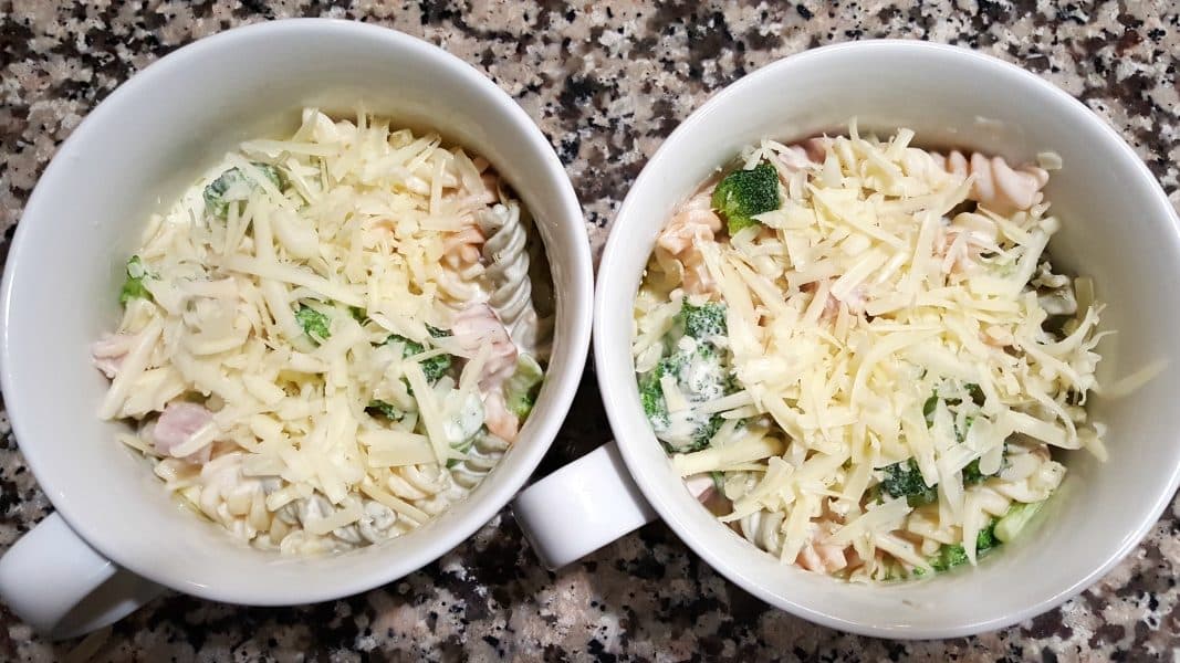 two oven safe dishes filled with cheesy ham broccoli casserole and topped with shredded cheese