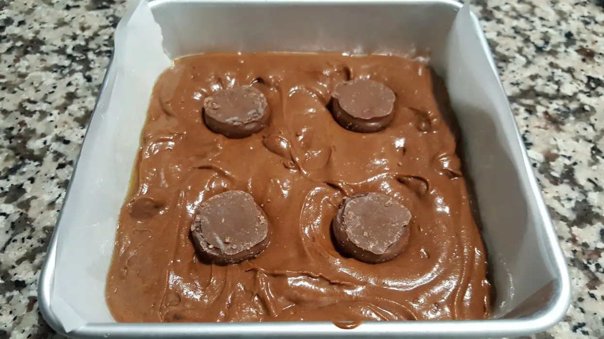 a cake pan filled with brownie batter and 4 upside-down chocolate covered cherries