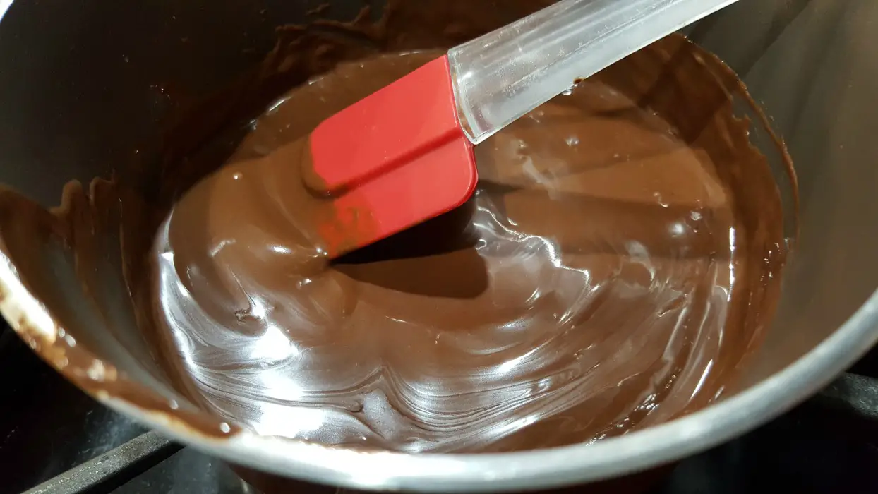 melted chocolate in a pan with red spatula.