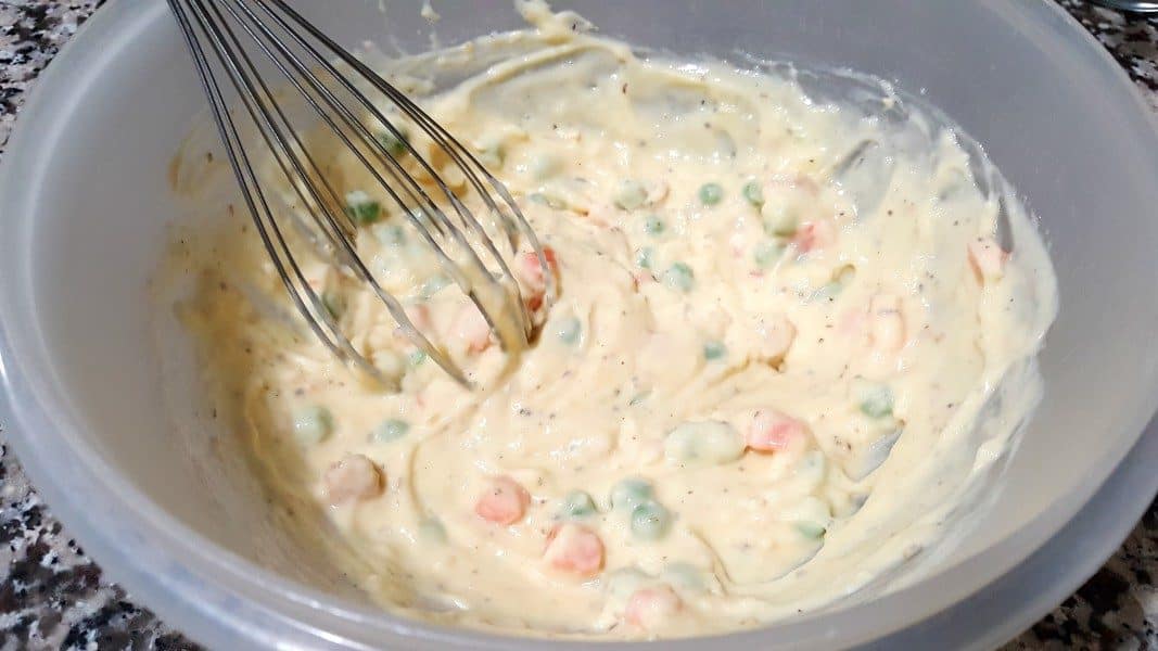frozen peas and carrots, milk, cream of chicken soup, salt, pepper, dried minced onions, melted butter, garlic powder, and Italian seasoning in a bowl with a whisk