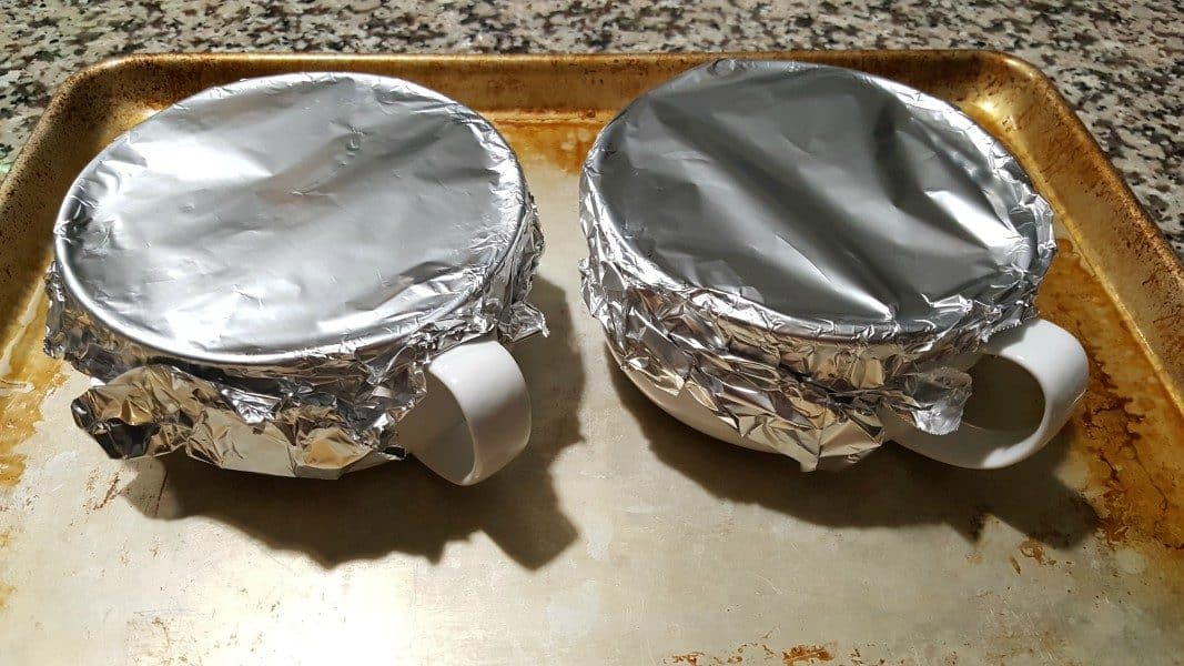 two baking dishes on a cookie sheet and covered with tinfoil