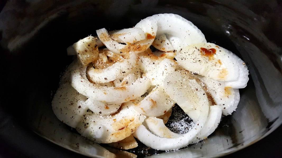 onions and seasonings in a slow cooker crock pot.