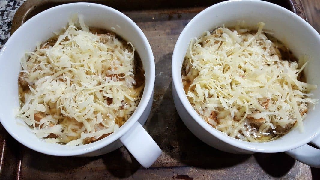 cheese sprinkled over soup and croutons in two soup bowls