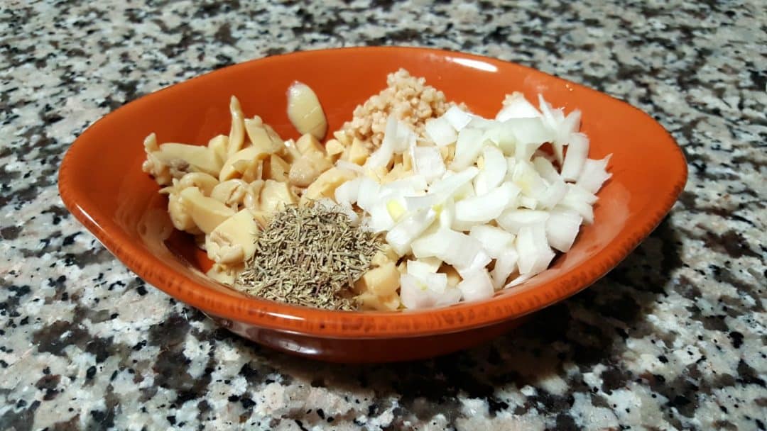 mushrooms, onion, garlic and thyme in an orange bowl.