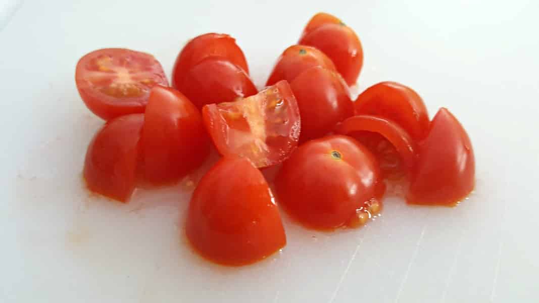 a pile of small cherry tomatoes diced into pieces.