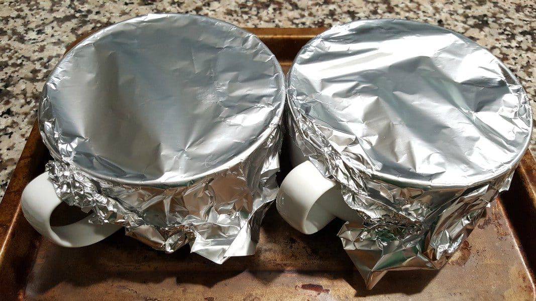 two bowls covered with foil on a baking sheet
