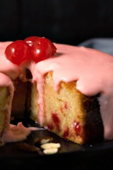 Glazed Cherry Almond Cake with a slice missing.