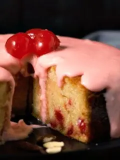 Glazed Cherry Almond Cake with a slice missing.