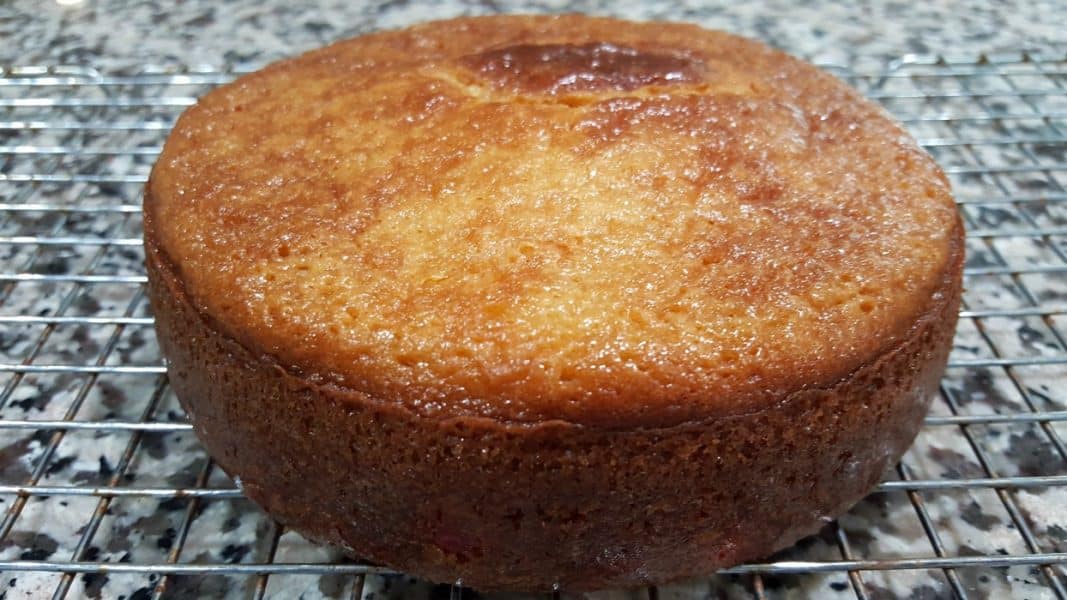 a baked 6 inch cherry cake cooling on a rack