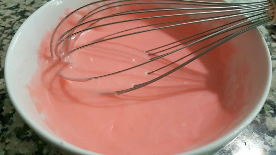 Cherry Glaze for Cake in a bowl with a whisk.