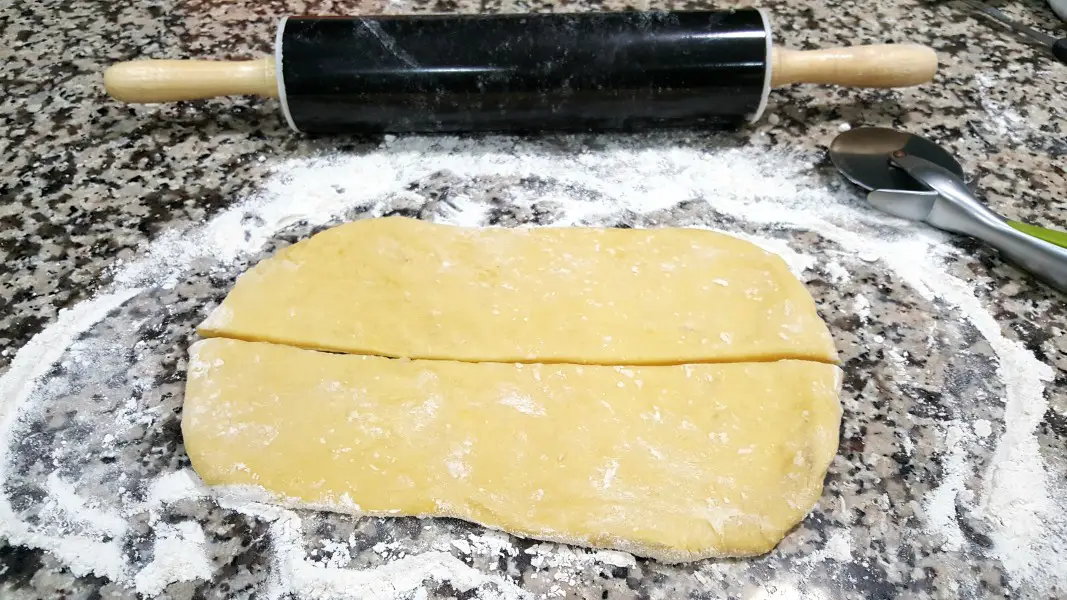 dough rolled out on a floured counter top cut in half lengthwise.