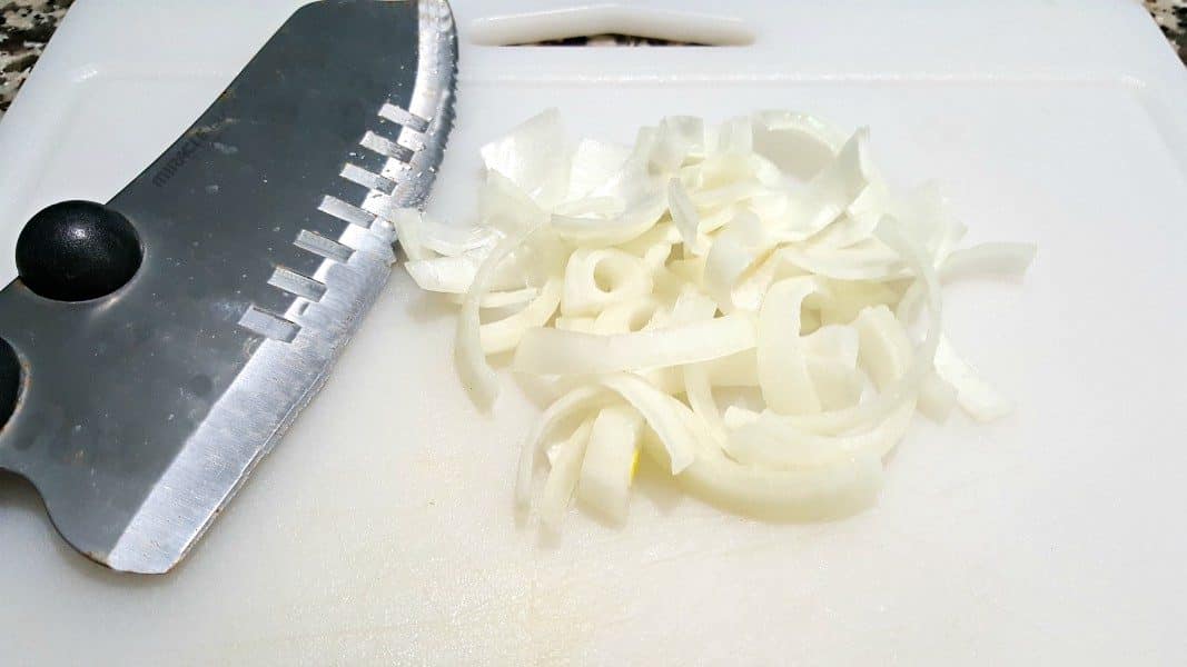 small white onion sliced thing on a cutting board with a chefs knife