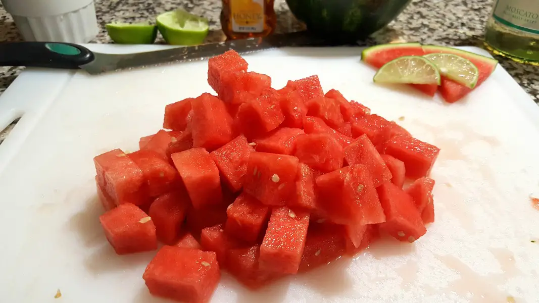 a pile of diced watermelon on a cutting board.